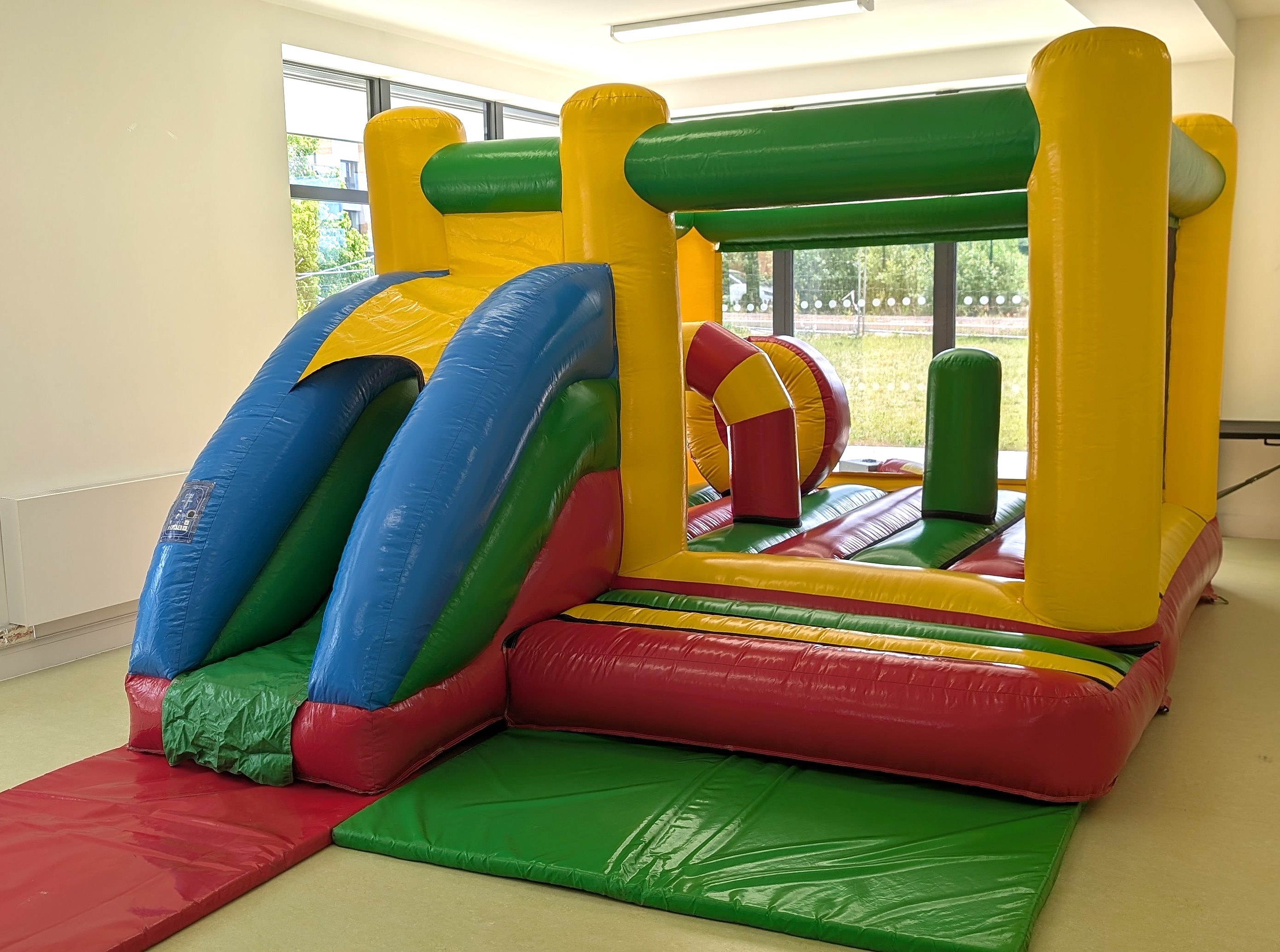 Multi Coloured Bouncy Castle with Slide Hire | GFC Leisure multi coloured bouncy castle with slide hire in the hub hall harlow