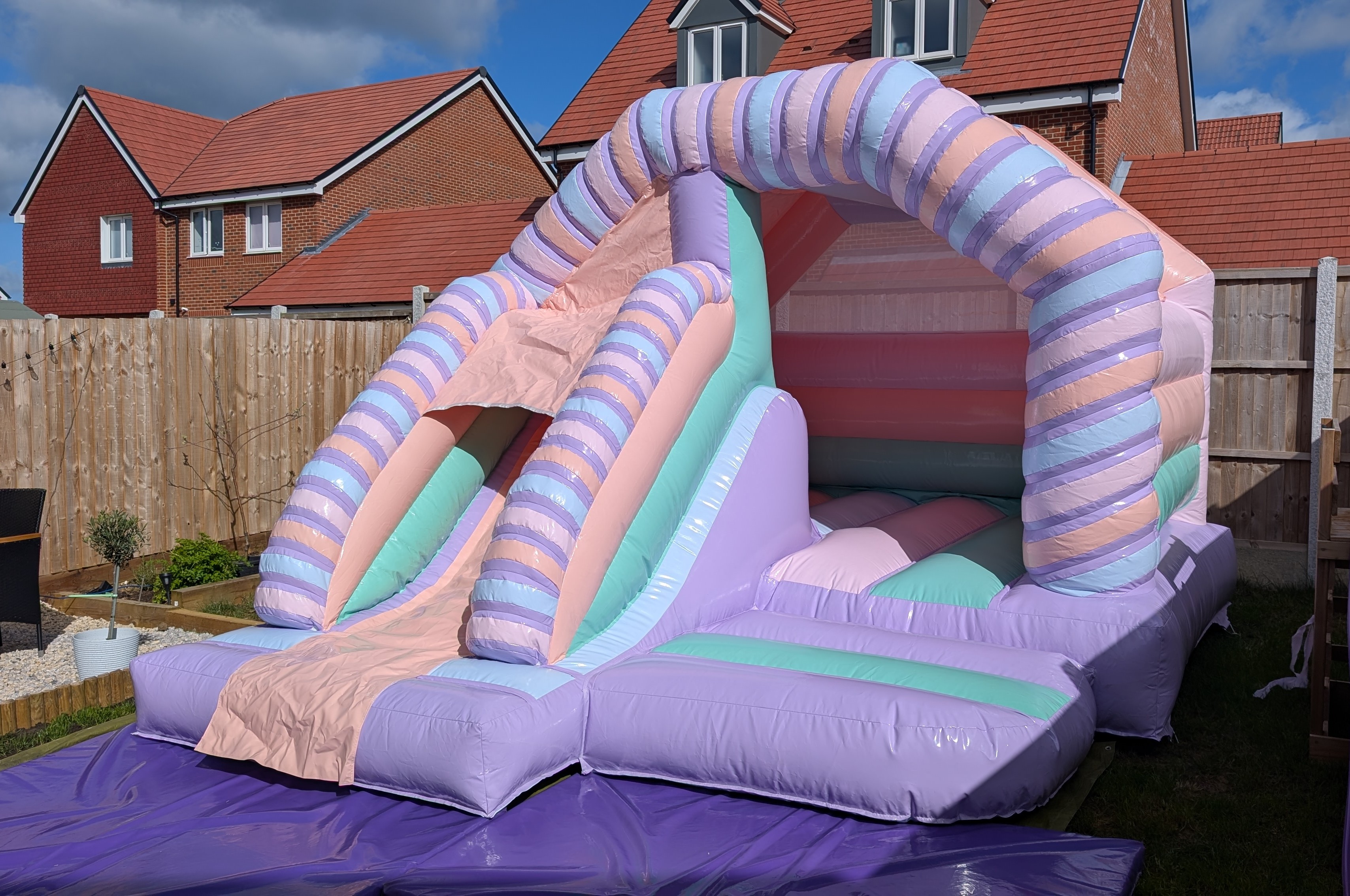 Pastel bouncy castle with slide hire in Bishop’s Stortford garden setup