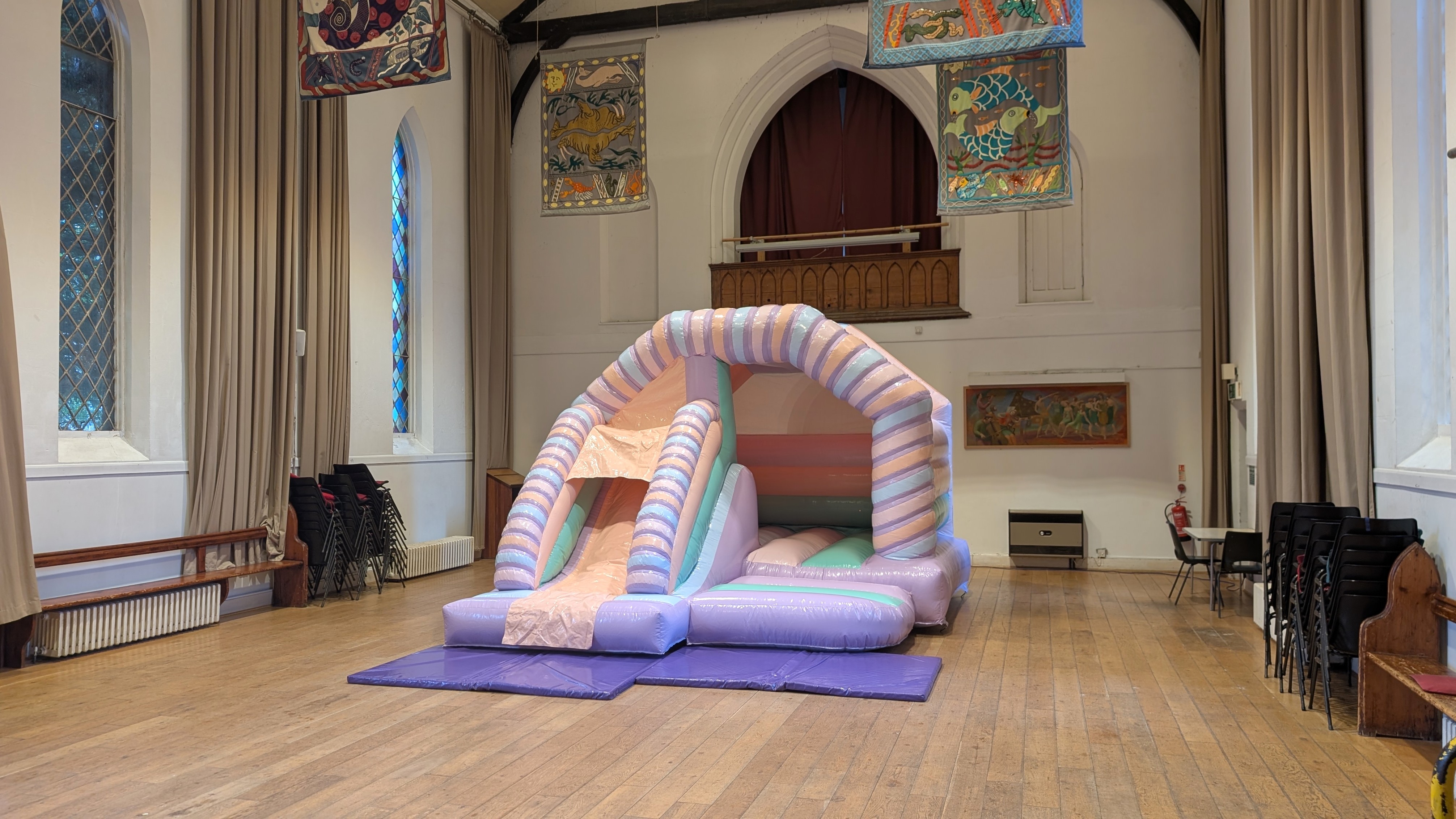 Pastel Bouncy Castle Hire in Harlow Pastel bouncy castle with slide set up in St Johns Arc Hall in Old Harlow