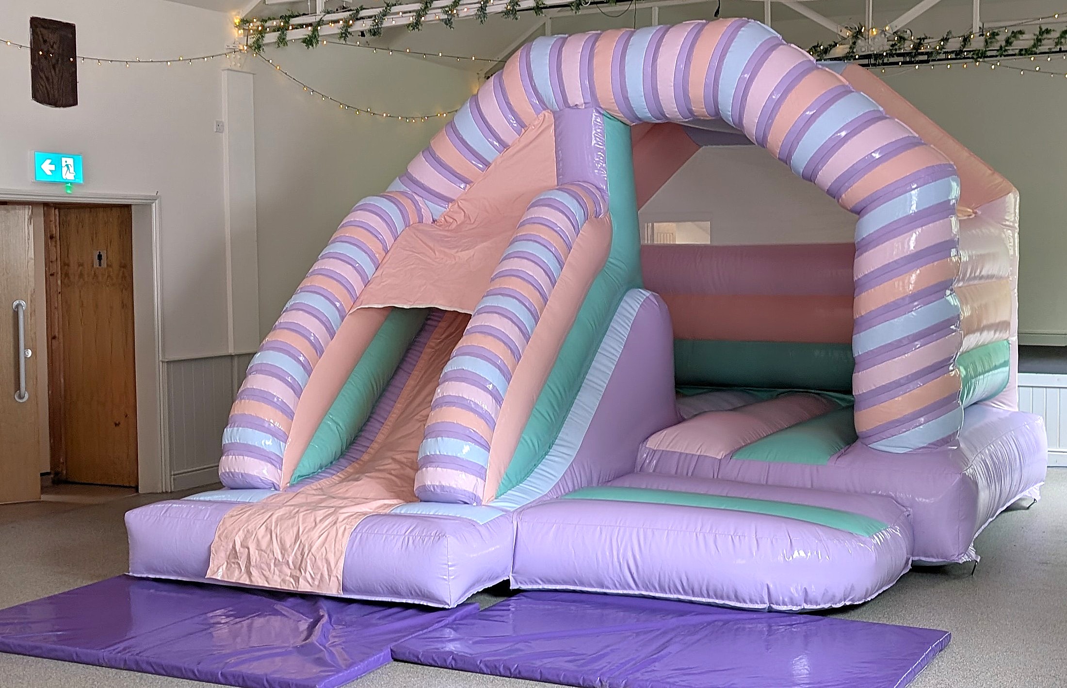 Pastel Bouncy Castle with Slide Hire | GFC Leisure Pastel bouncy castle with slide hire in Henham Village Hall indoor setup