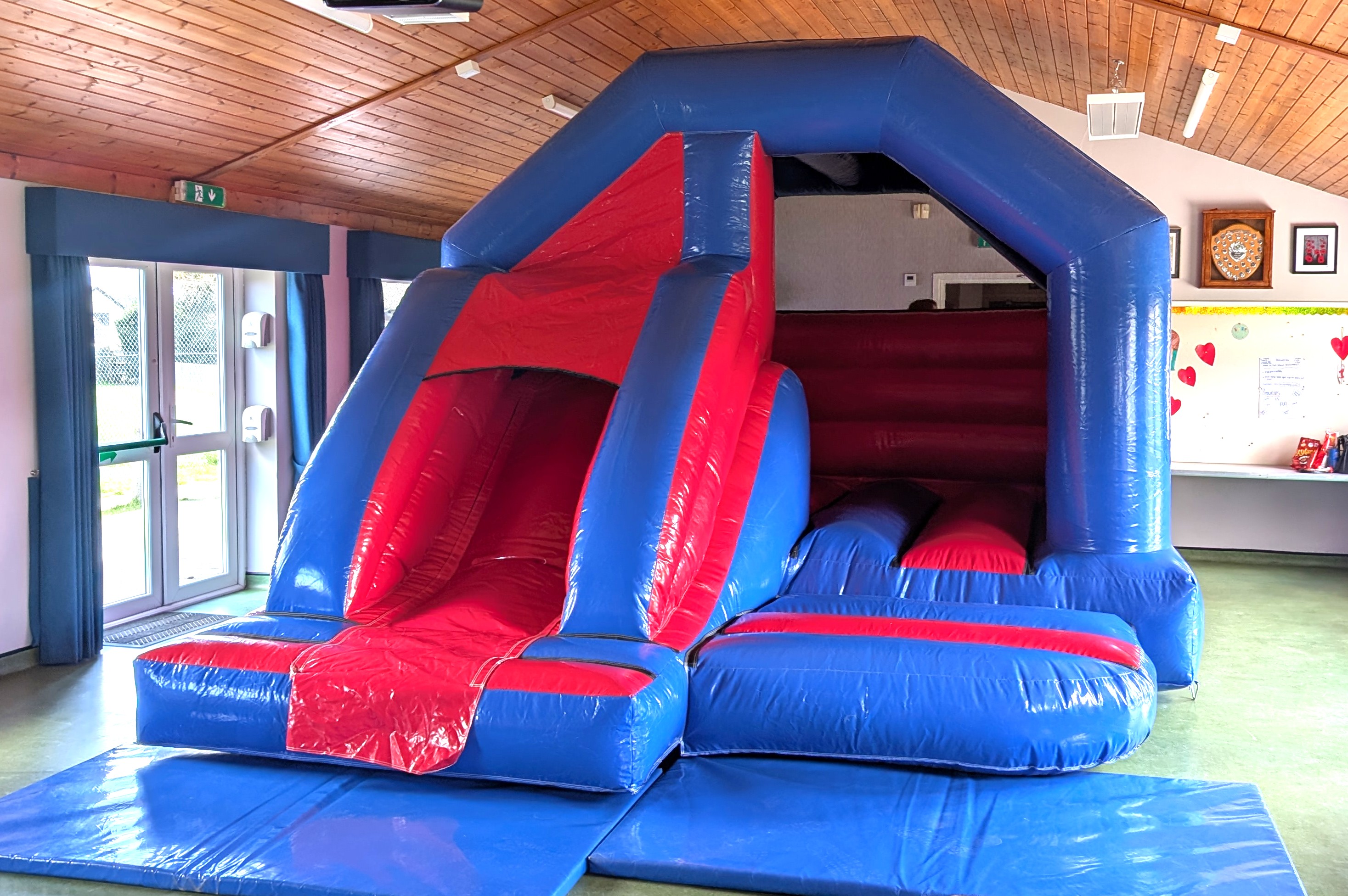 Red and blue bouncy castle with slide hire set up in Elsenham memorial hall