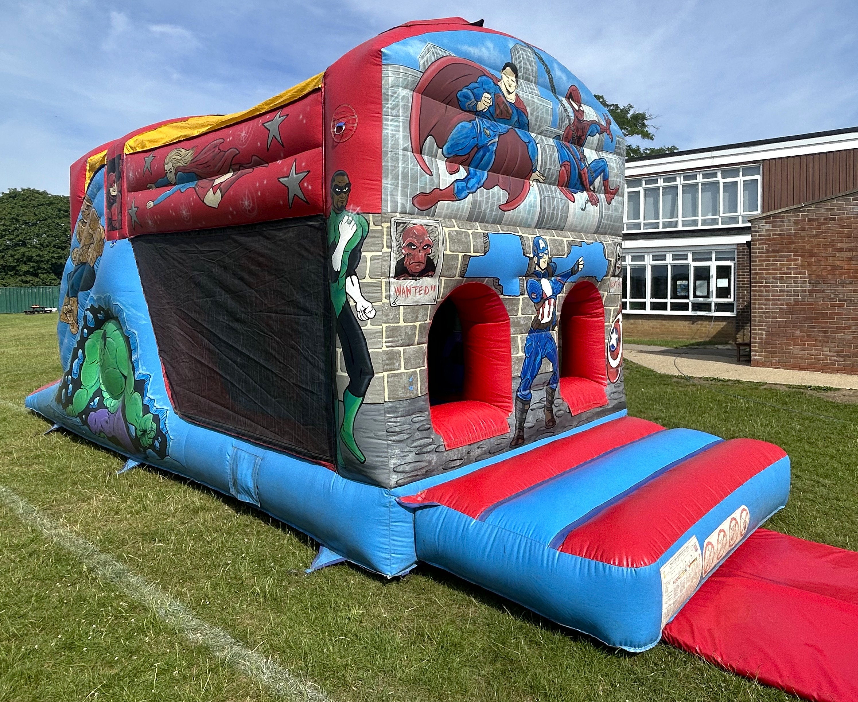 Book superhero inflatable obstacle course with slide Superhero inflatable obstacle course with slide hire set up at a school in Harlow Essex